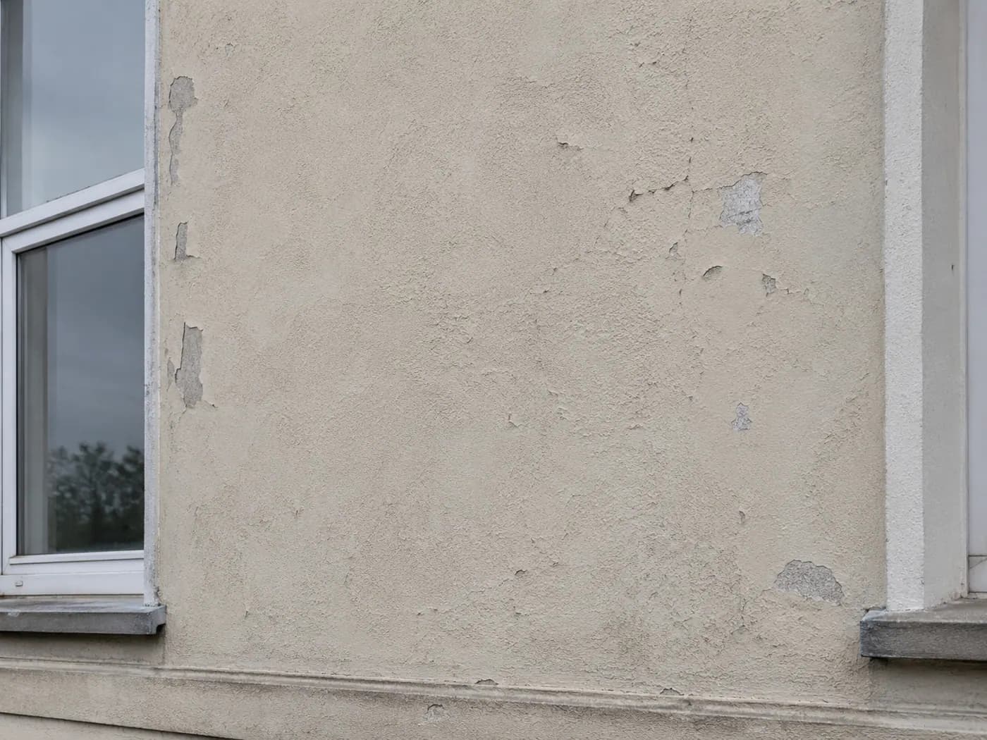 KI-generiertes Bild: Nordfassade des fiktiven Musterhauses mit Rissbildung im Putz